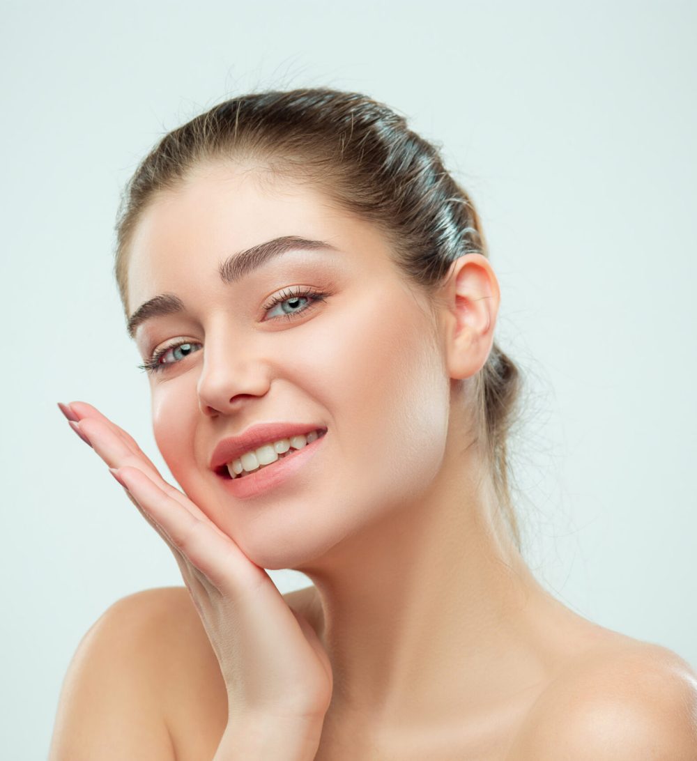 The beautiful female face. The perfect and clean skin of face on gray
